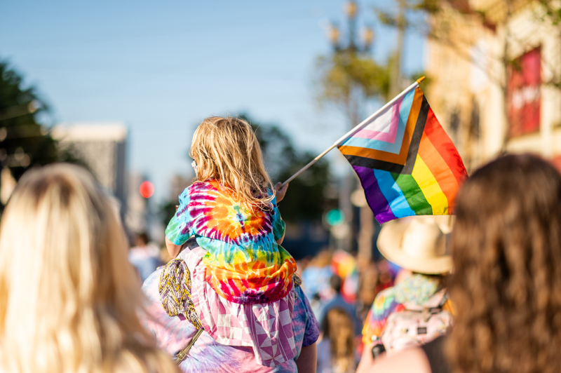 Young girl in rainbow on the shoulder of an adults. Transmarch