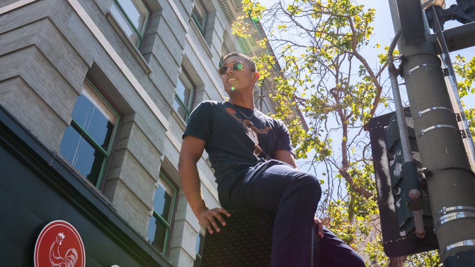 Warriors fan sits on top of light post.