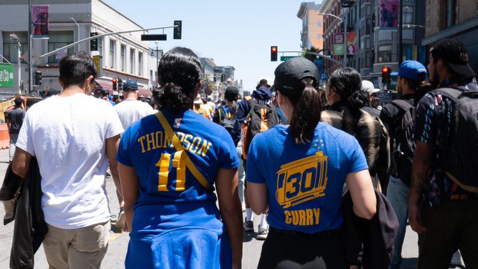 Two Warriors fans wear Klay Thompson and Steph Curry shirts.