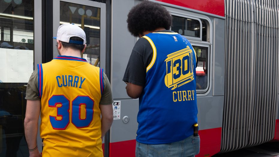 Warriors fans wait for the bus wearing Steph Curry shirts.