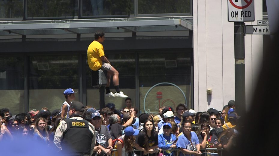 A Warriors fan sits on top of a lamp post.