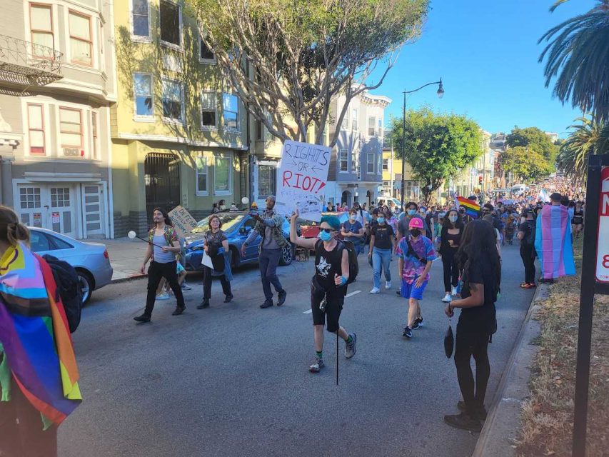 Trans march with a sign saying Rights or Riot