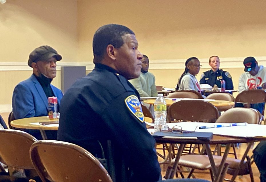 a police chief sitting at a pubic meeting.