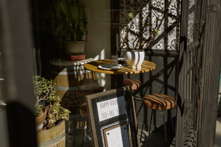 The inside of a room, with a table and chairs, seen through a window.