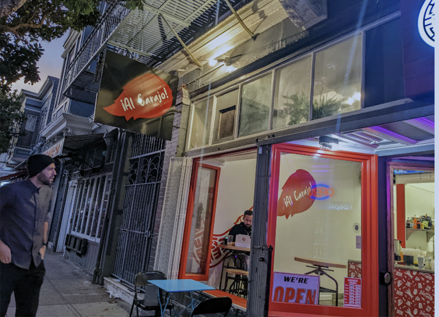 The outside of a taqueria with a man looking in the restaurant.