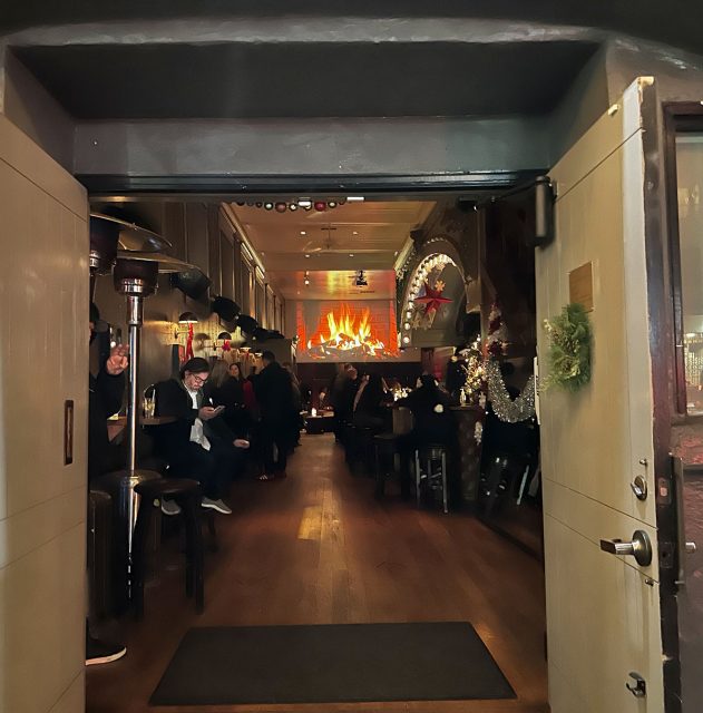 Looking through a big door at a fireplace.