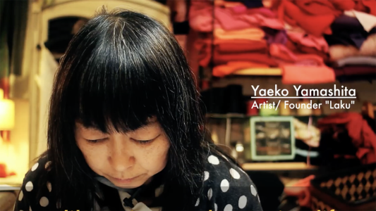 A woman, head slightly down as she works behind the counter of a store