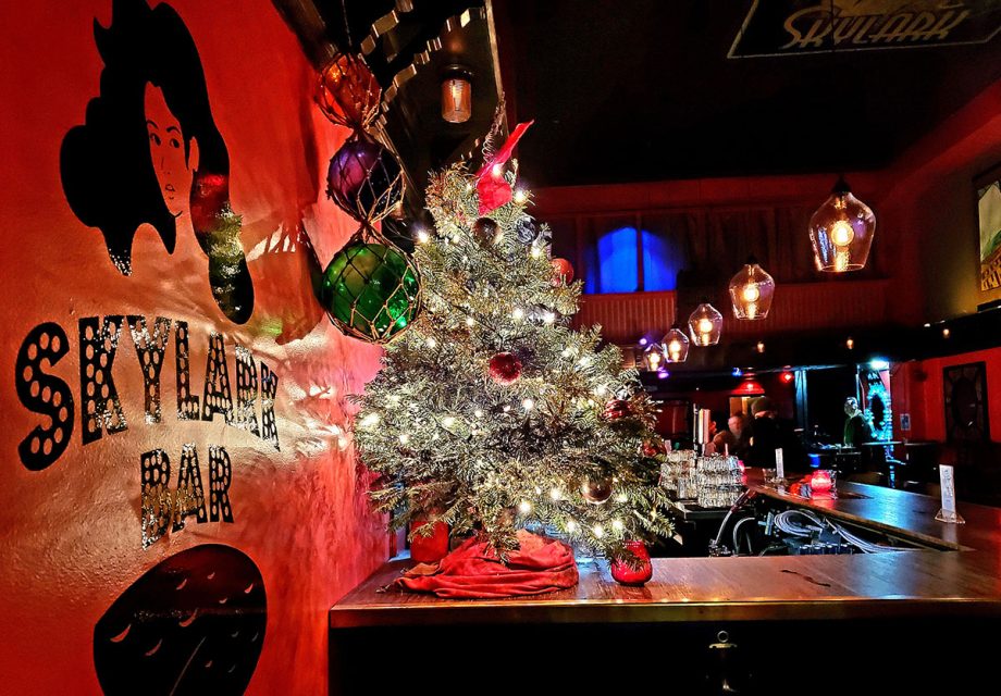 A Christmas tree on top of a bar, with lights across it.