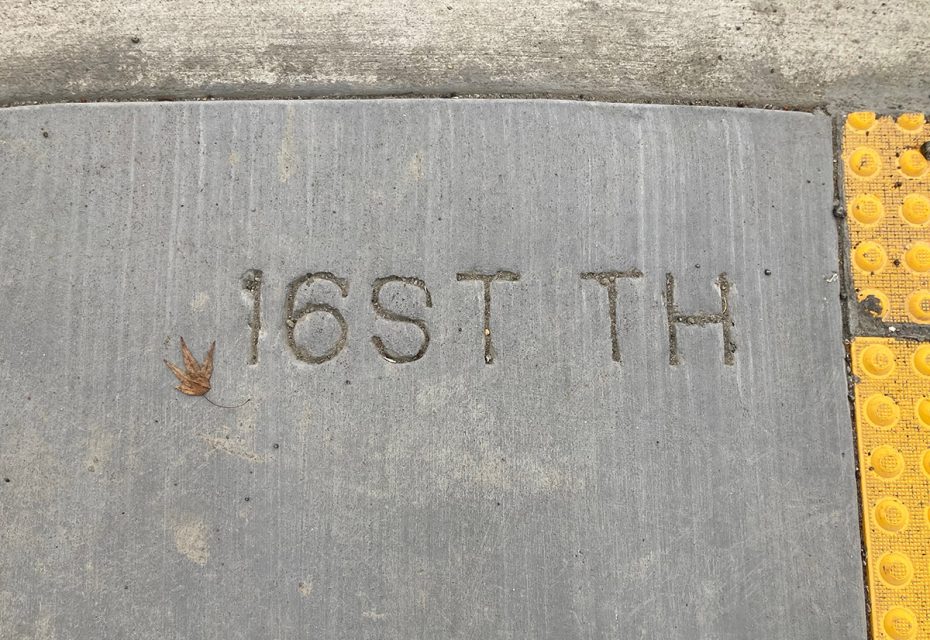 A sidewalk with a misspelled street name cut into the cement.