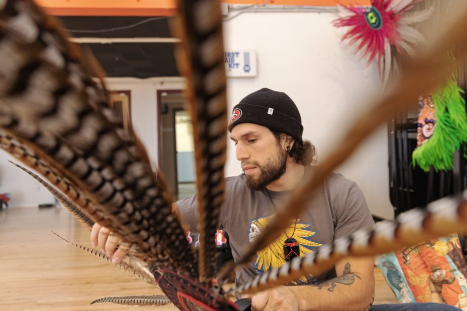 A man sitting and a feather in front of him.