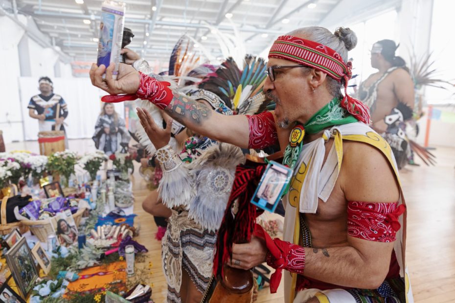 A dancer lifting a candle at a small altar of offerings.