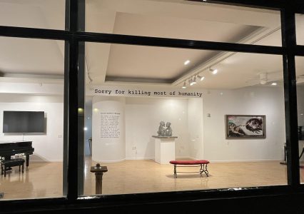 Looking through the museum window at paintings and other installations.