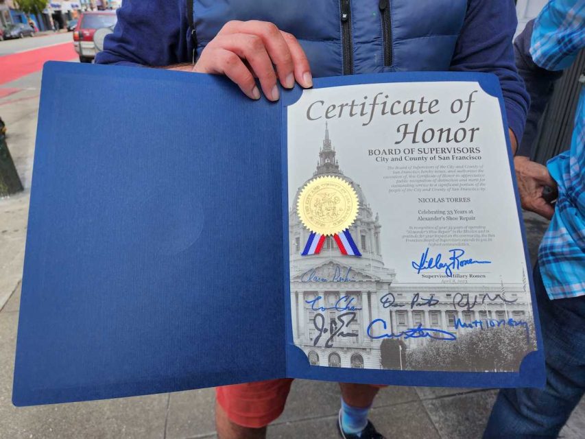 A man holds a certificate from SF board of supervisors.