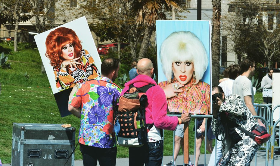 Posters being held high with drag figures.