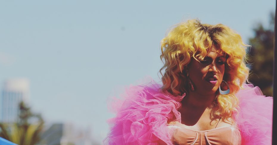 A person in drag with a pink boa.