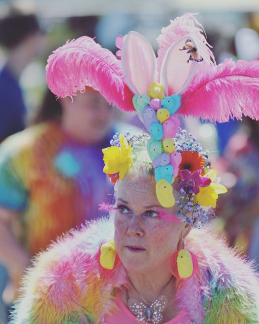 A woman with colored feathers and marshmaallow peeps in her hair and a boa.