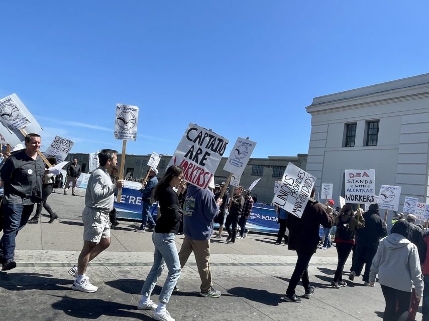 A group of Alcatraz Cruises workers walking with signs