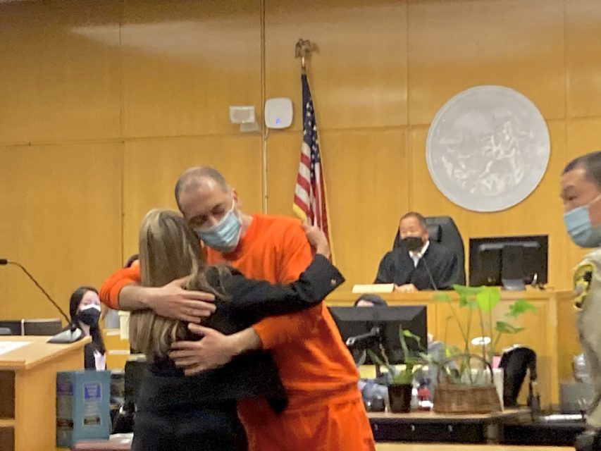 Nima Momeni, alleged killer of Bob Lee, in a orange prison clothing, hugging his attorney.
