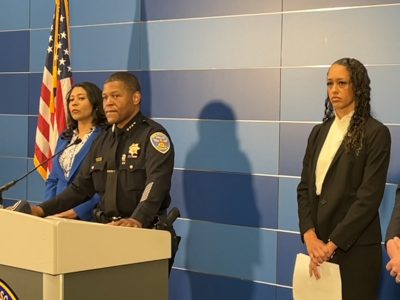 Three officials stand at a podium