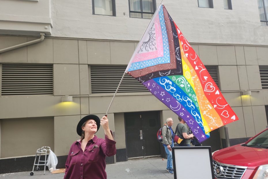 Marcher Jess Hele waving a rainbow flag.