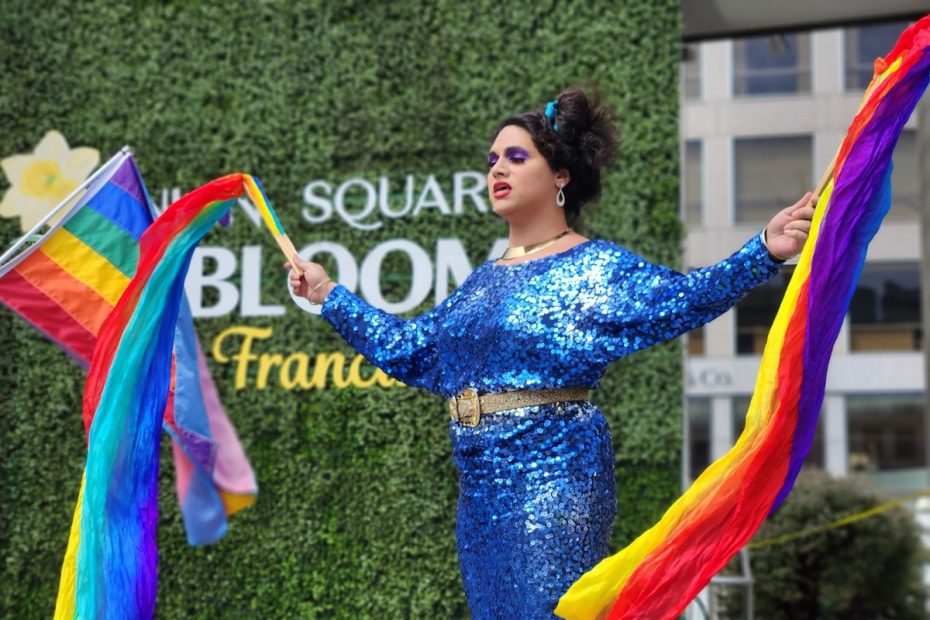 A drag performer waving rainbow flags.