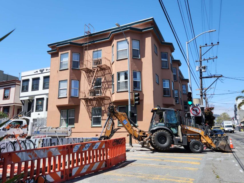 backhoe next to a trench in the street