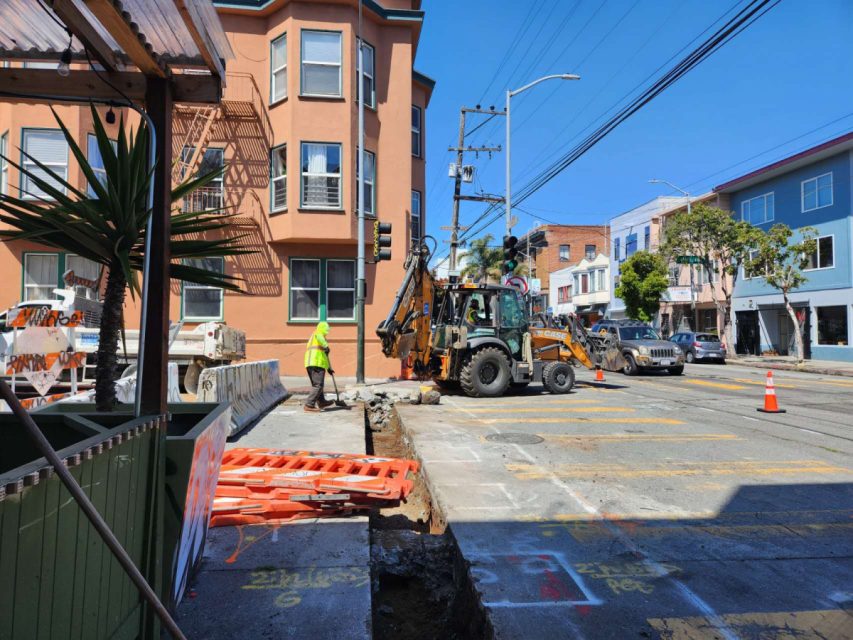 backhoe next to a trench in the street
