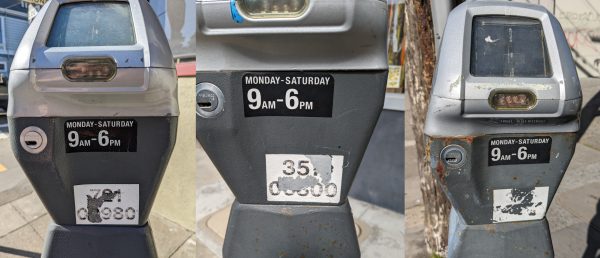 Three parking meters with their numbers scratched off.