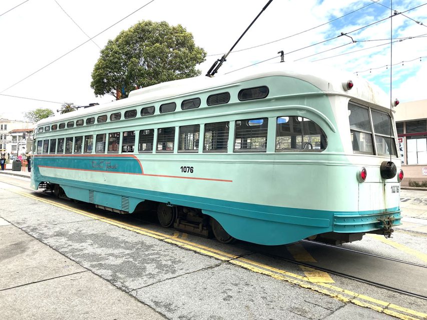 A long green streetcar with the. number 1076