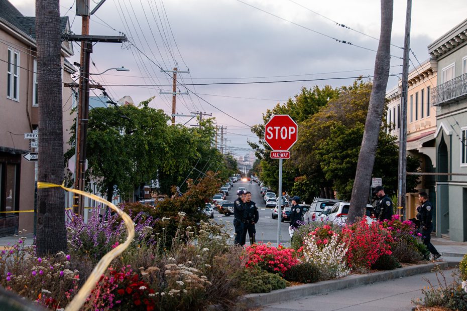 A medium with red and white flowers and uniformed officers in the back.A stop sign.
