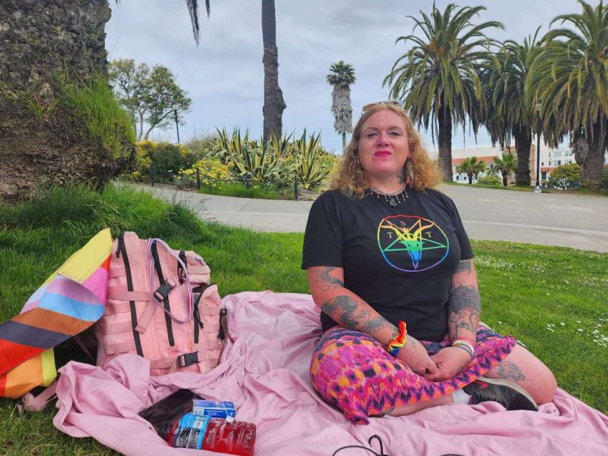 a person sitting on a pink blanket before the Trans March