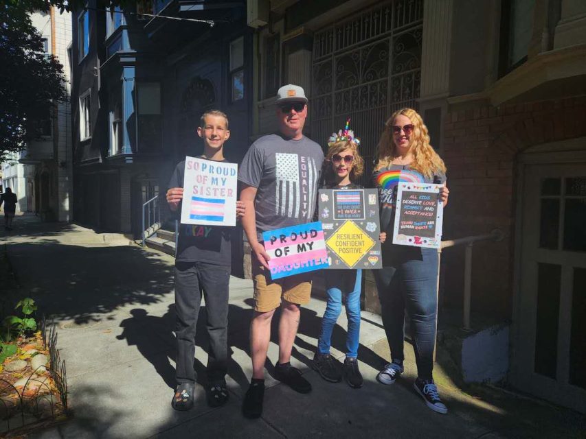 a family of four standing on the street for the Trans March