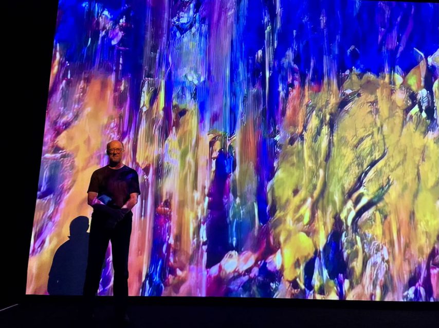 A person standing in front of a colorful background.