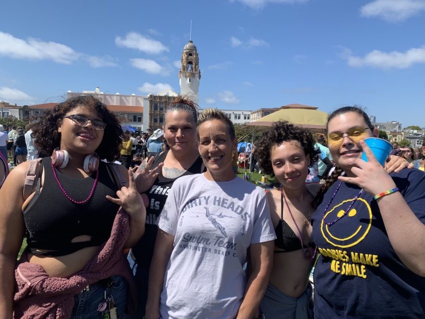 A group of women wearing a variety of shirts. A couple talk about boobies.