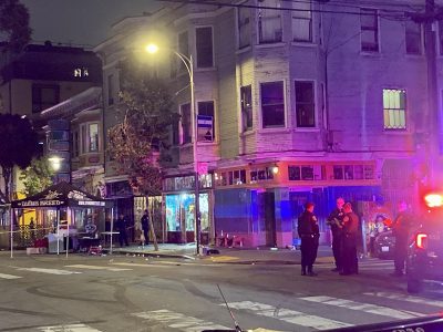 Police near a street corner. Debris and a tent that reads "Dying Breed" are nearby.
