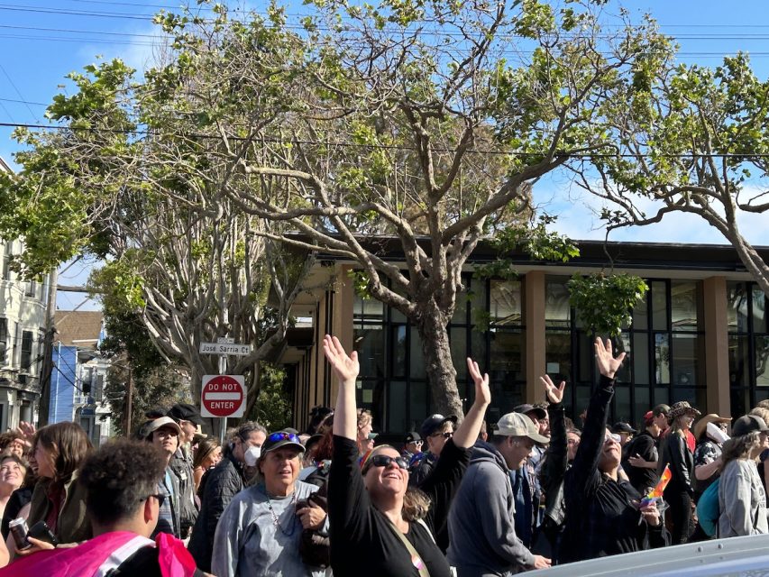 A crowd reaching their hands up to catch falling necklaces. 