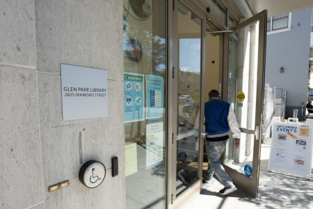 A photo of a man opening a door of a library and walking in.