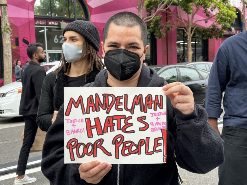Protester holding a "mandelman hates poor people" sign