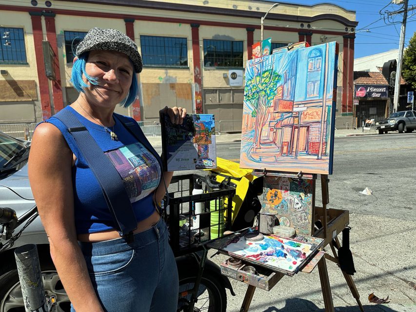 A woman in front of a painting easel outside, the ainting is of a bar. 