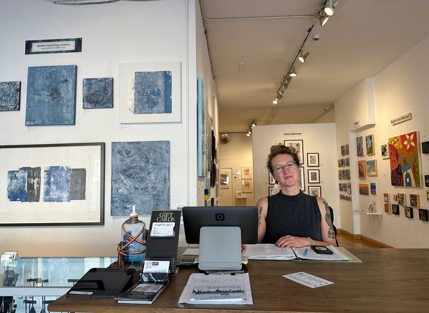 a woman sitting at a desk in an art gallery.