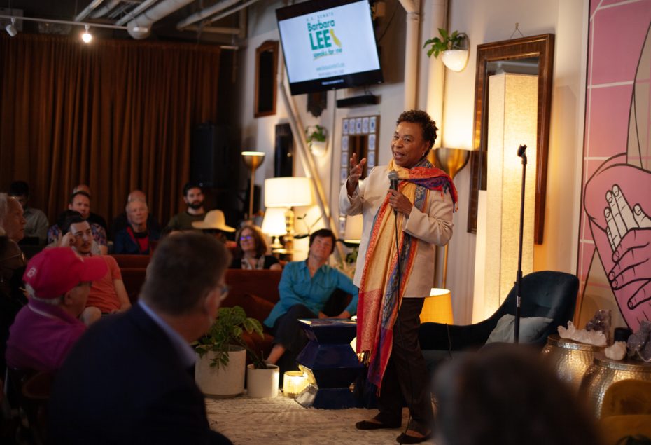 A woman with a orange scarf on stage and standing.