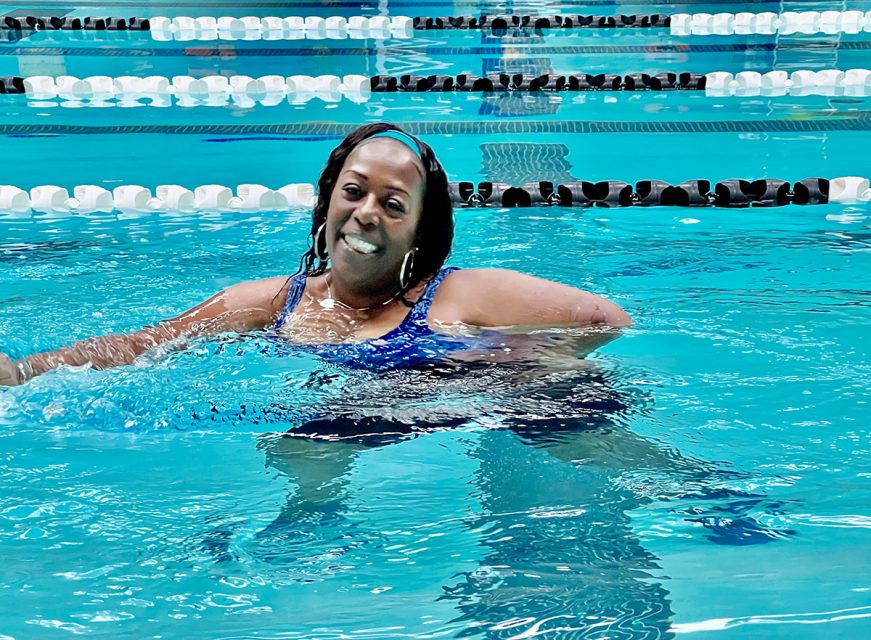 A lone woman in a swimming pool between lanes.