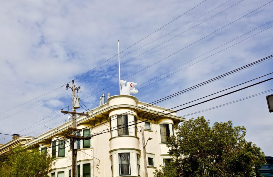 A white building with a white inflated figure on the roof.