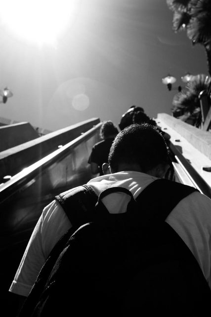 A black and white photo of a person on an escalator.