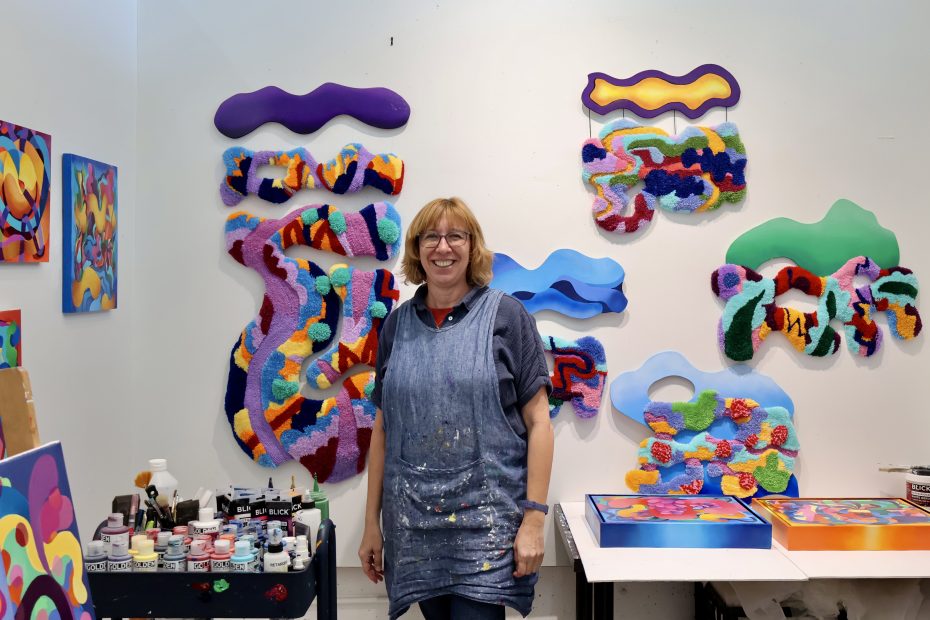 A woman standing in front of a colorful art studio.