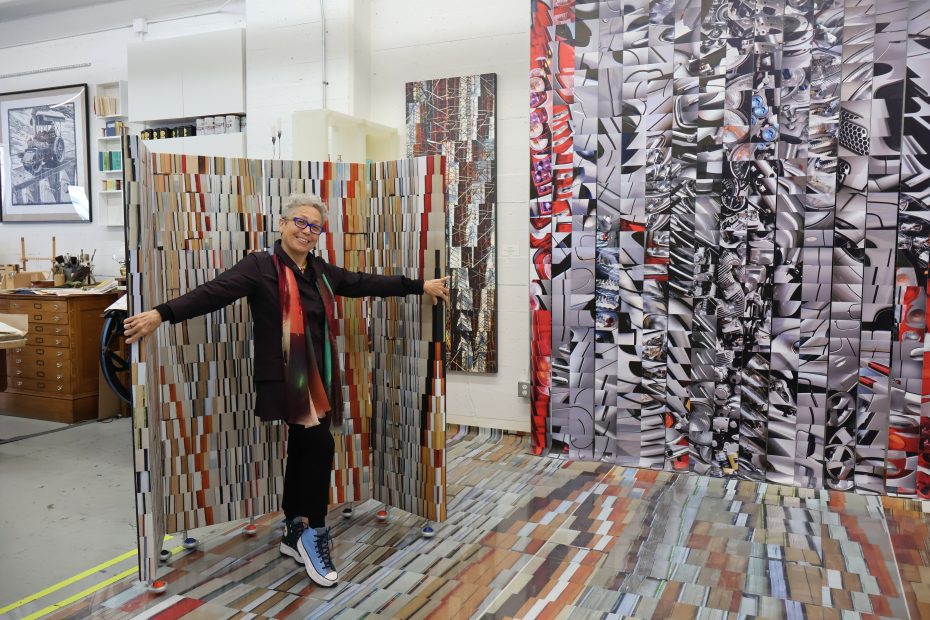 A woman standing in front of a large piece of art.