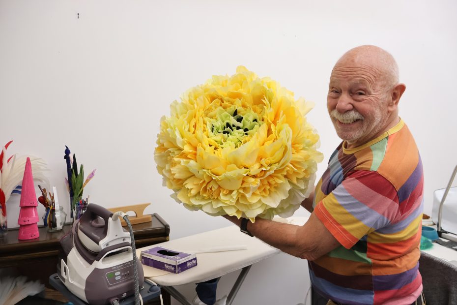 An older man holding a large yellow flower.