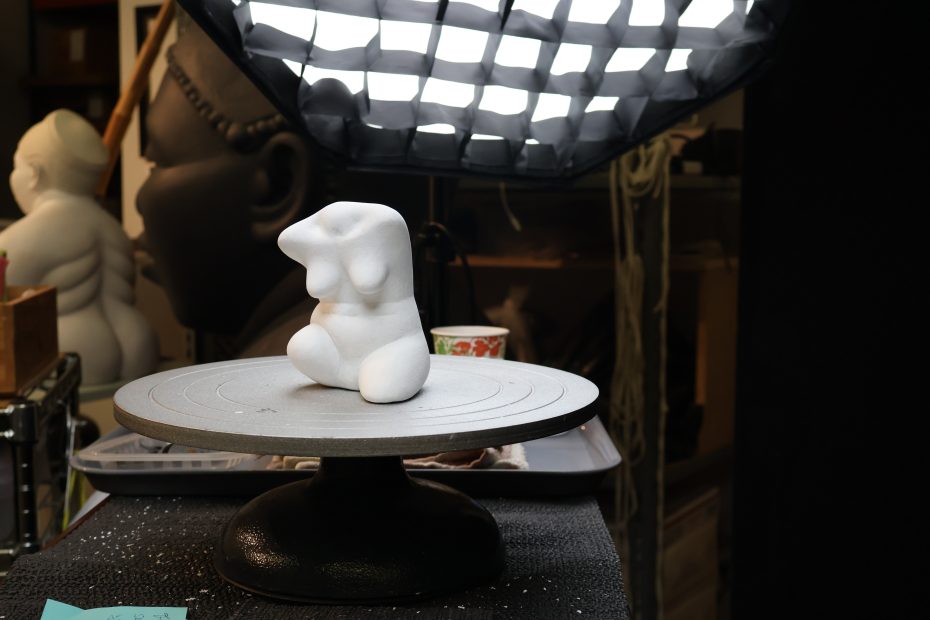 A statue on a table in front of a light.