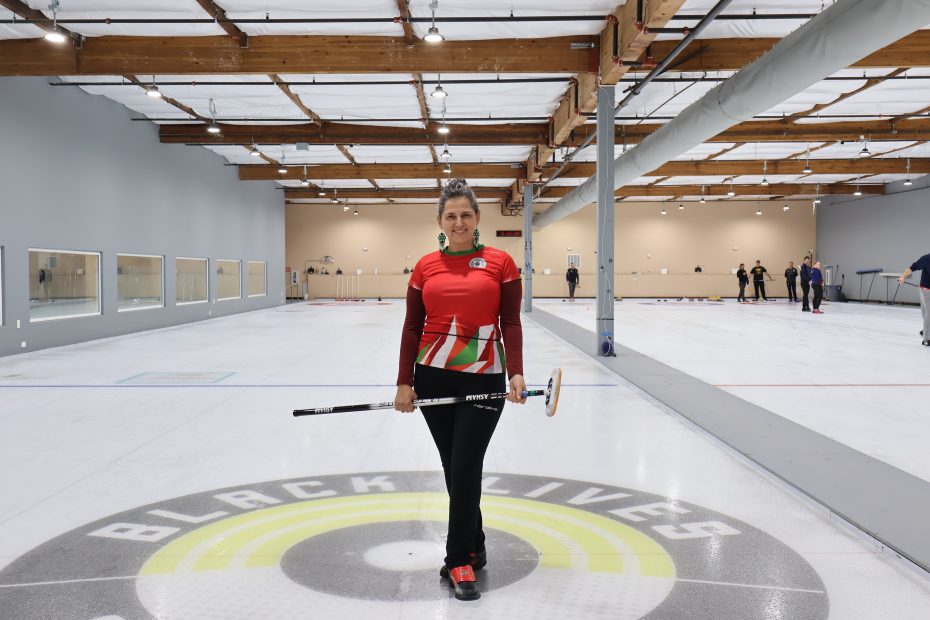 A woman holding a curling stick in a curling rink.