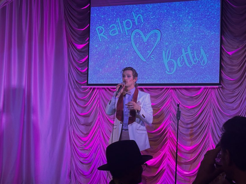 A man is singing on stage at a party.